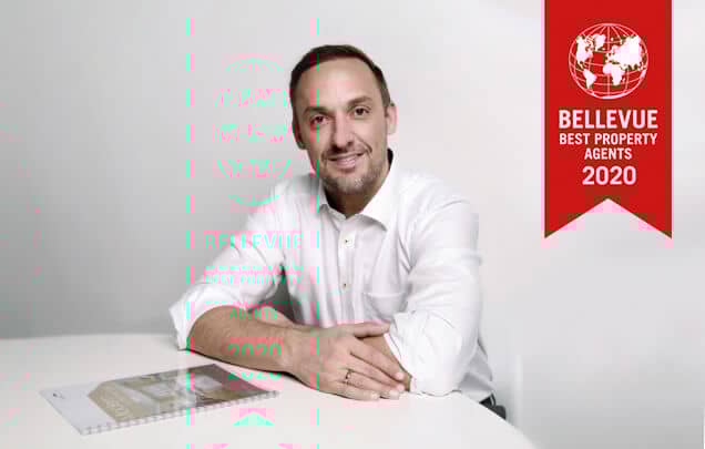 Innenaufnahme eines hellen Bürozimmers in Seitenperspektive mit weißem Tisch und Präsentationsunterlagen im Vordergrund