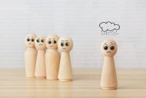 Gruppierung von fünf Holzfiguren davon eine isoliert unter gezeichneter Regenwolke in Frontansicht