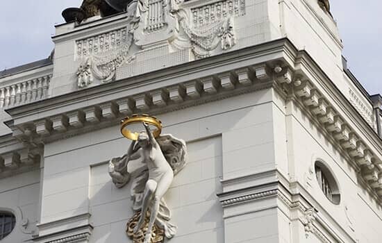 historisches Stadthaus in Froschperspektive mit weißer Stuckfassade mit Figurenrelief und rundem Oberlicht