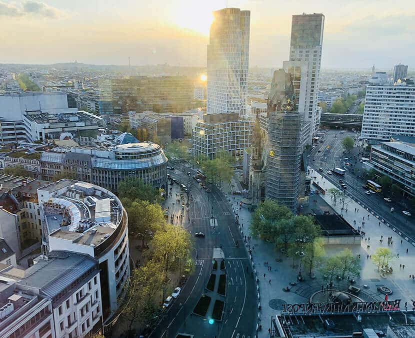 Vogelperspektive auf Hochhausensemble und Denkmalkirche an breiter belebter Straße mit Abendsonne