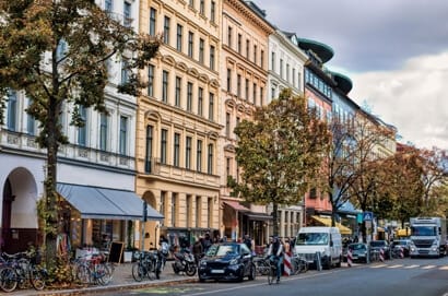 Stadspand met meerdere verdiepingen en boetiekjes op de begane grond Balkons Bakstenen gevel en herfstbomen