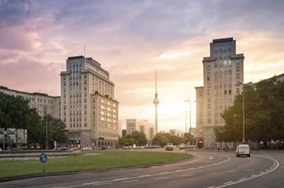 Vooraanzicht van twee gebouwen met meerdere verdiepingen, gevel van baksteen en televisietoren op de achtergrond