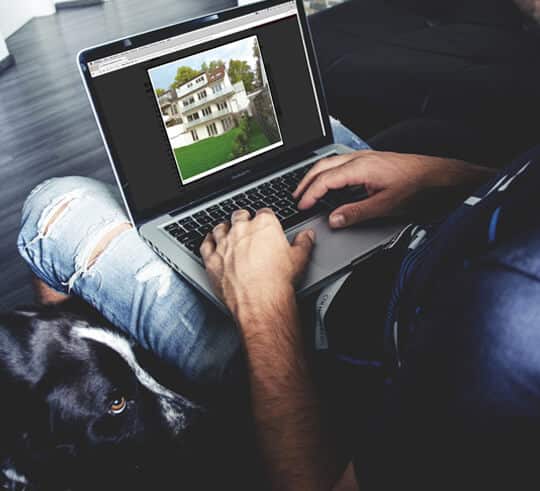 dreigeschossige Villa in Frontalansicht mit Satteldach, Balkon und großem Garten