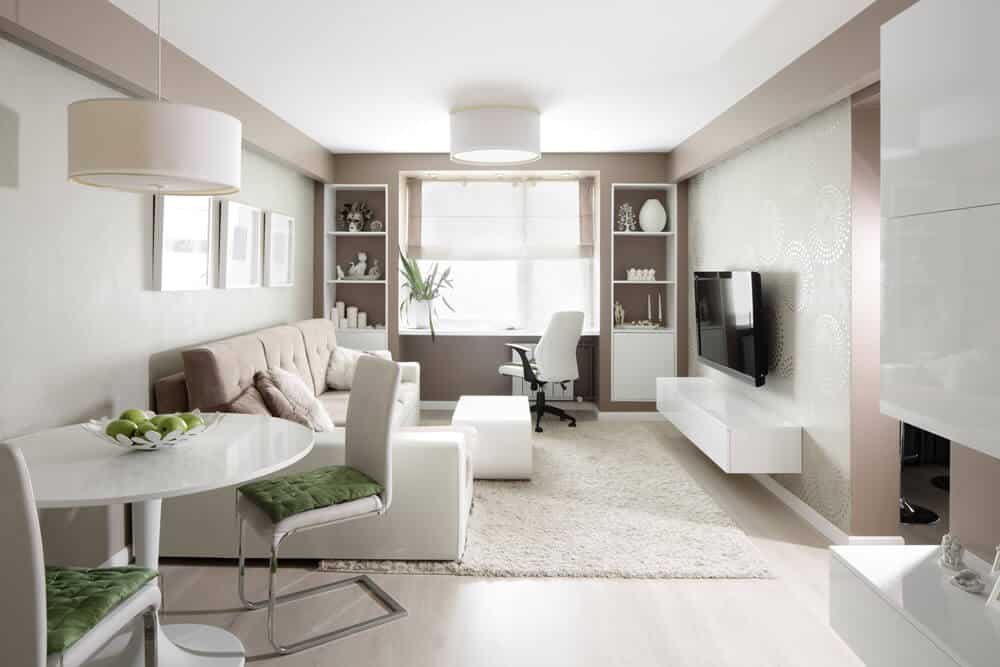 Salon/salle à manger lumineux dans un appartement moderne en perspective frontale avec canapé table à manger panneau TV et poste de travail à la fenêtre