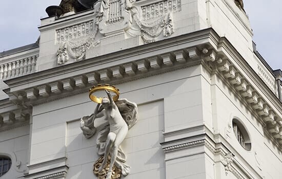 Historisch herenhuis in kikkerperspectief met wit stucwerk gevel met figuurreliëf en rond dakraam