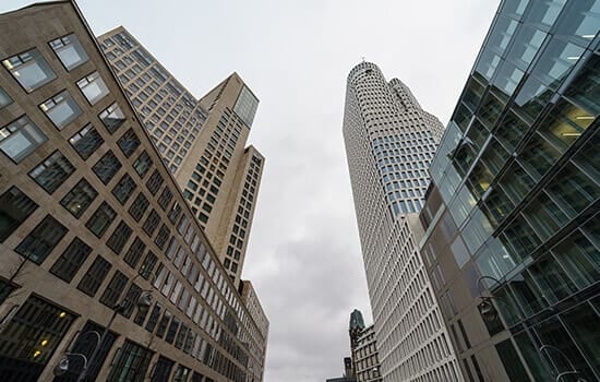 Onderaanzicht van modern hoogbouwensemble met ronde geveltoren en glazen puien bij bewolkt weer