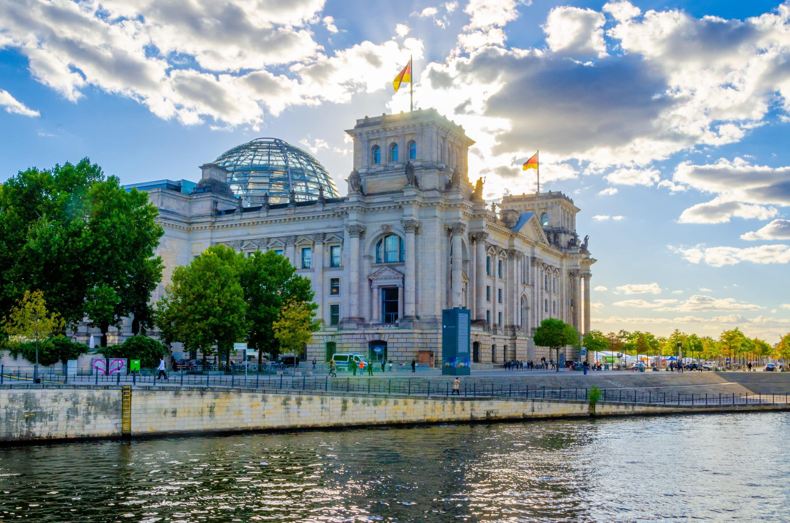 Reichstagsgebäude in Berlin am Spreeufer mit Glaskuppel und deutscher Flagge Frontperspektive