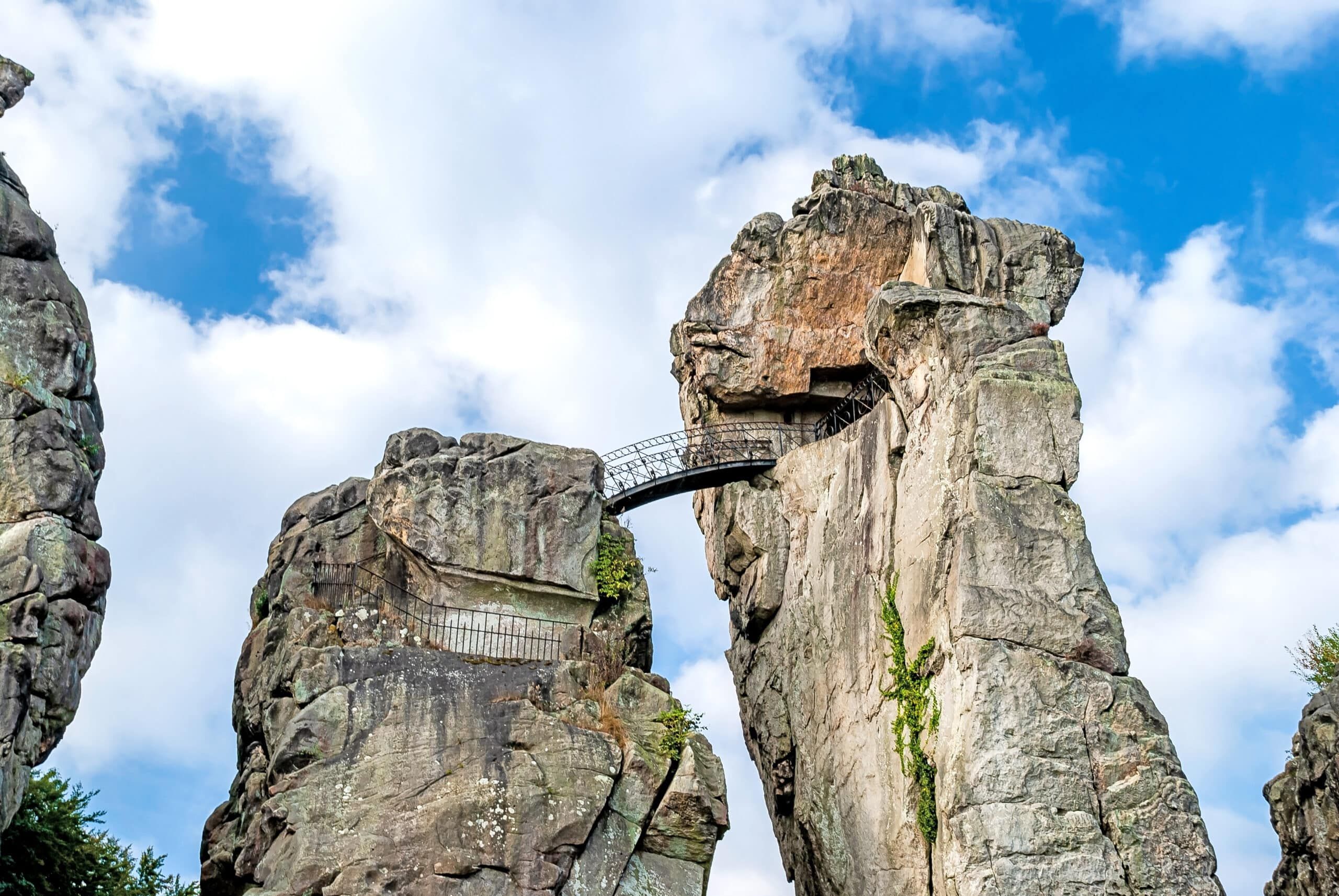 一个巨大岩层的侧视图，有一座狭窄的钢桥和部分绿化的表面