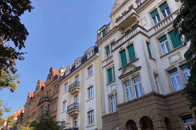Kikkeruitzicht op historische flatgebouwen met balkons en groene luiken