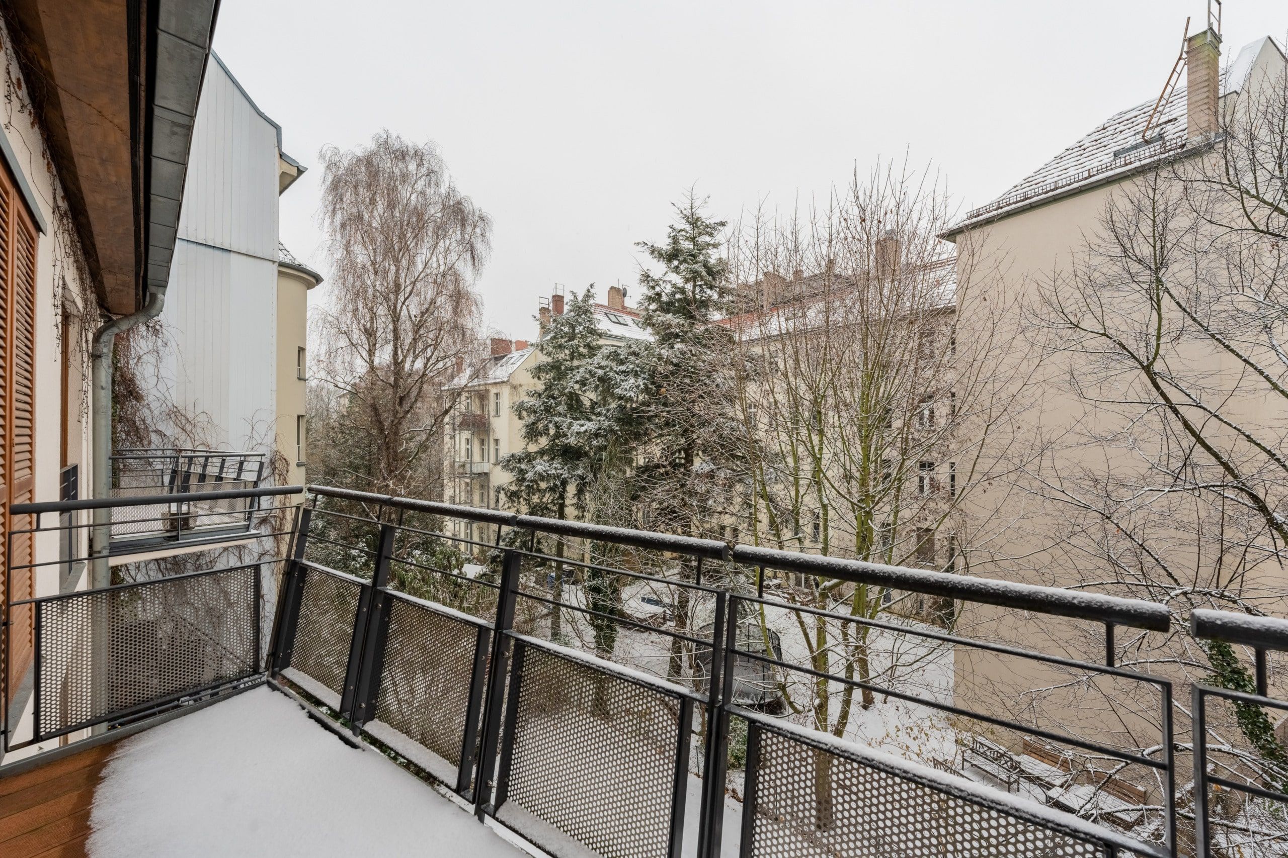 Schneebedeckter Stadtbalkon mit Metallgeländer in moderner Etagenwohnung blick in winterlichen Innenhof