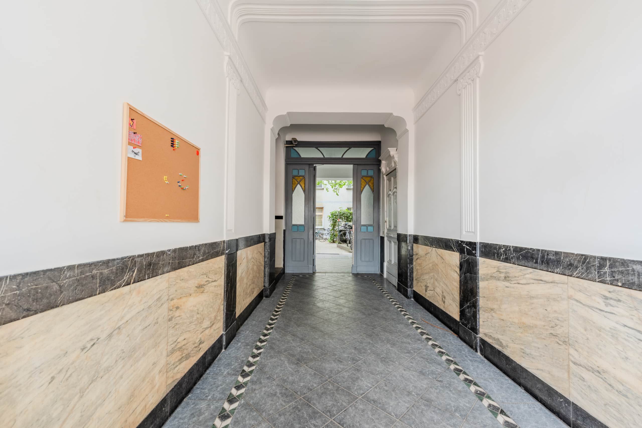 Innenansicht Hauseingangskorridor mit Marmorvertäfelung und Blick durch Doppeltür in Innenhof