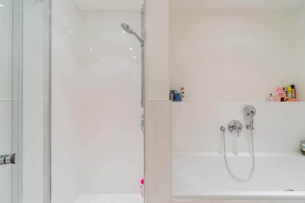 Innenansicht modernes Bad mit bodengleicher Glasdusche und eingelassener Badewanne in Neubauwohnung