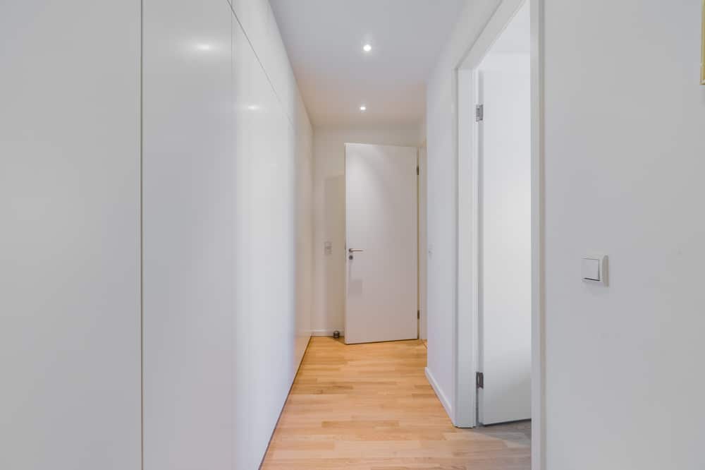 Flur einer modernen Wohnung mit hellem Echtholzdielenboden Einbauschrank weißen Türen und Deckenstrahlern