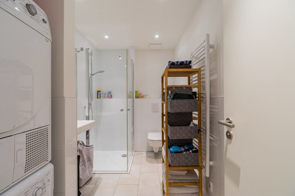 Innenaufnahme Apartment-Bad mit ebenerdiger Dusche, Hänge-WC, Handtuchheizkörper und Korbregal