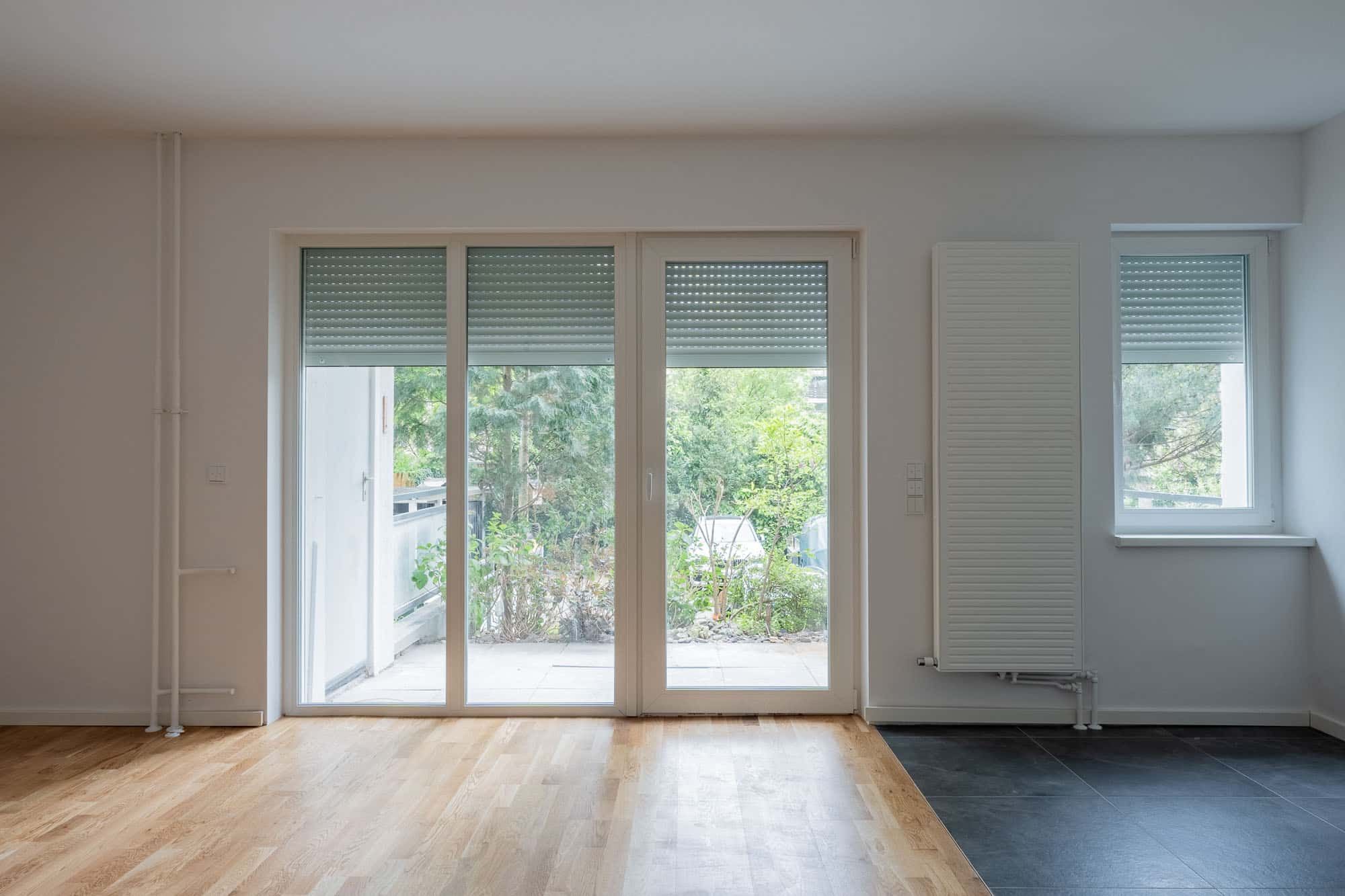 Erdgeschosswohnung mit bodentiefen Fenstertüren zur Terrasse Innenansicht Parkett und Fliesenboden Rollläden