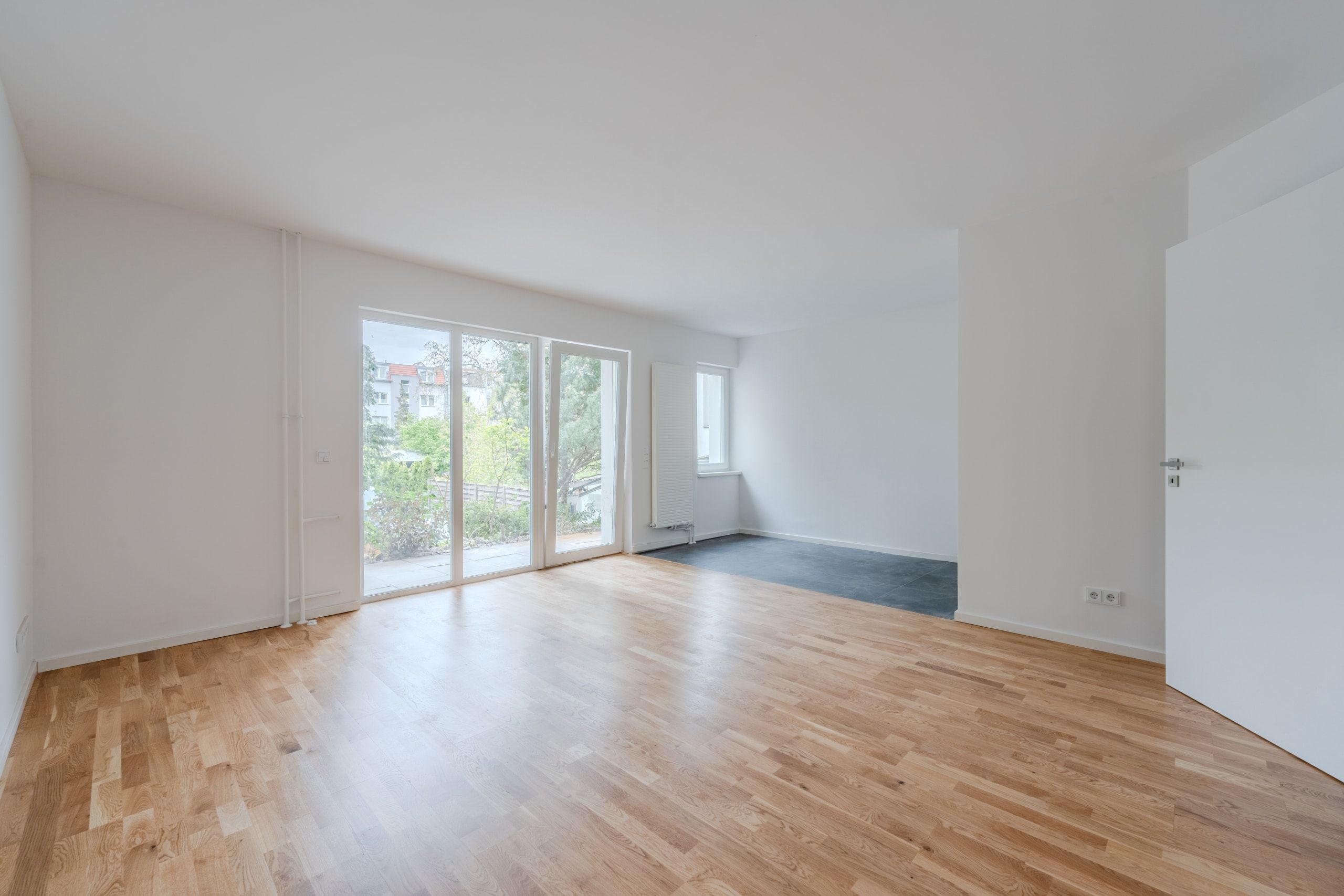 Innenansicht Wohnung mit Parkettboden und bodentiefer Glasfront zum Garten
