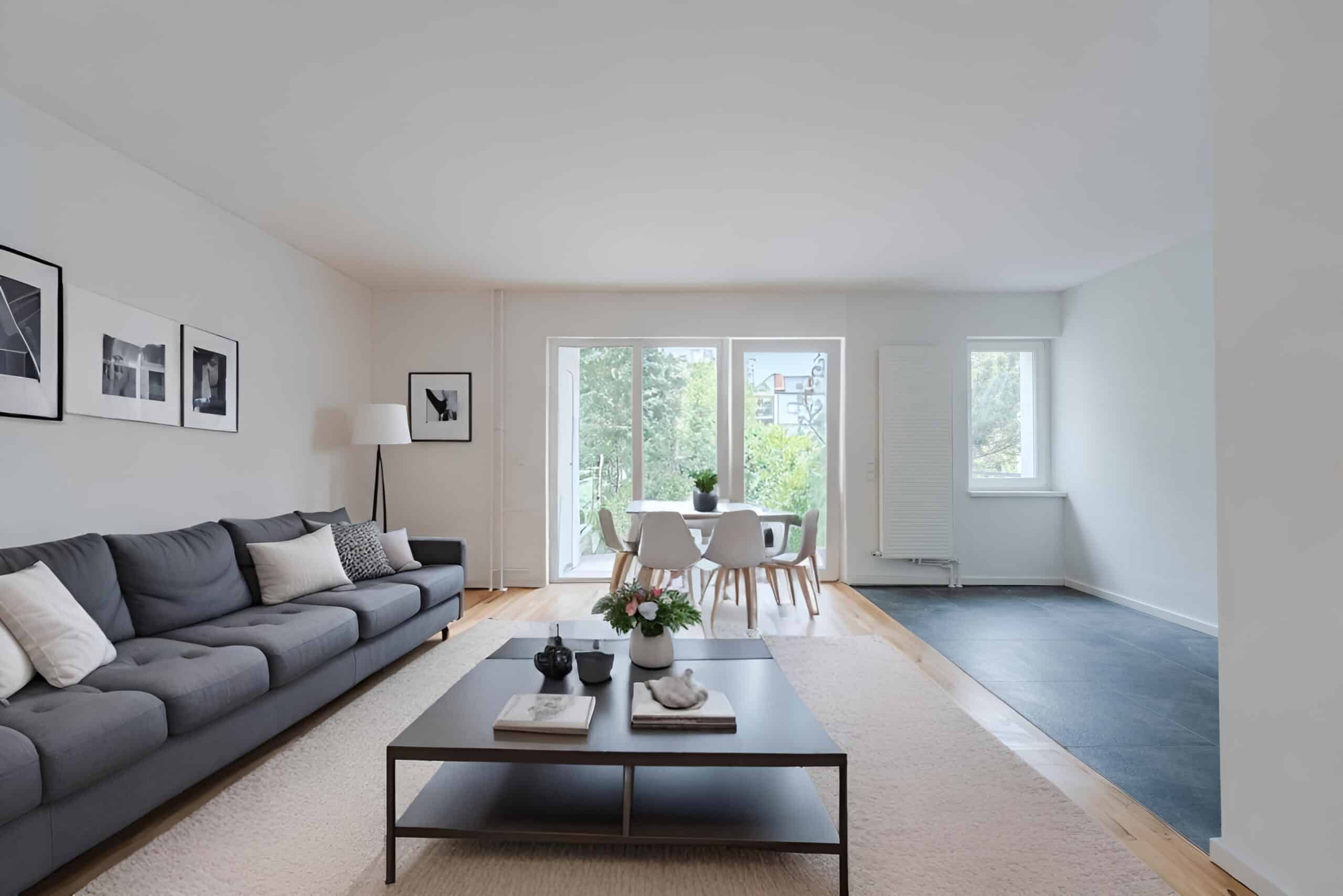 Offener Wohn- und Essbereich mit grauem Sofa Couchtisch und Essplatz vor bodentiefen Fensterfronten