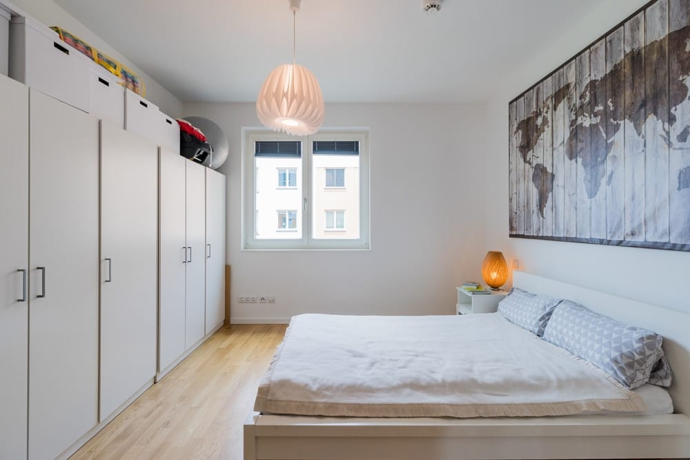 Innenansicht modernes Schlafzimmer mit Doppelbett weiße Einbauschränke Fenster und dekorative Weltkarte an Wand