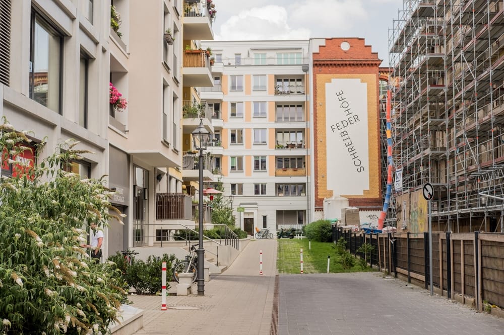 Hinterhofperspektive auf moderne Mehrfamilienhäuser mit Balkonen und Klinkerfassade sowie begrünter Innenhof