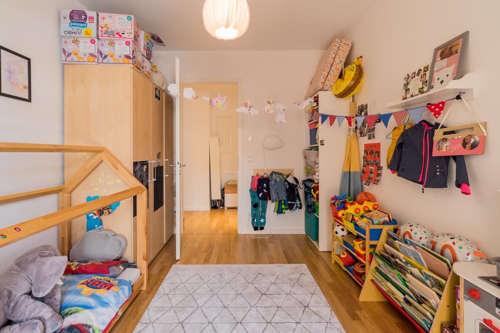 Innenansicht Kinderzimmer einer Wohnung mit Hausbett, Parkettboden und Spielzeugregal