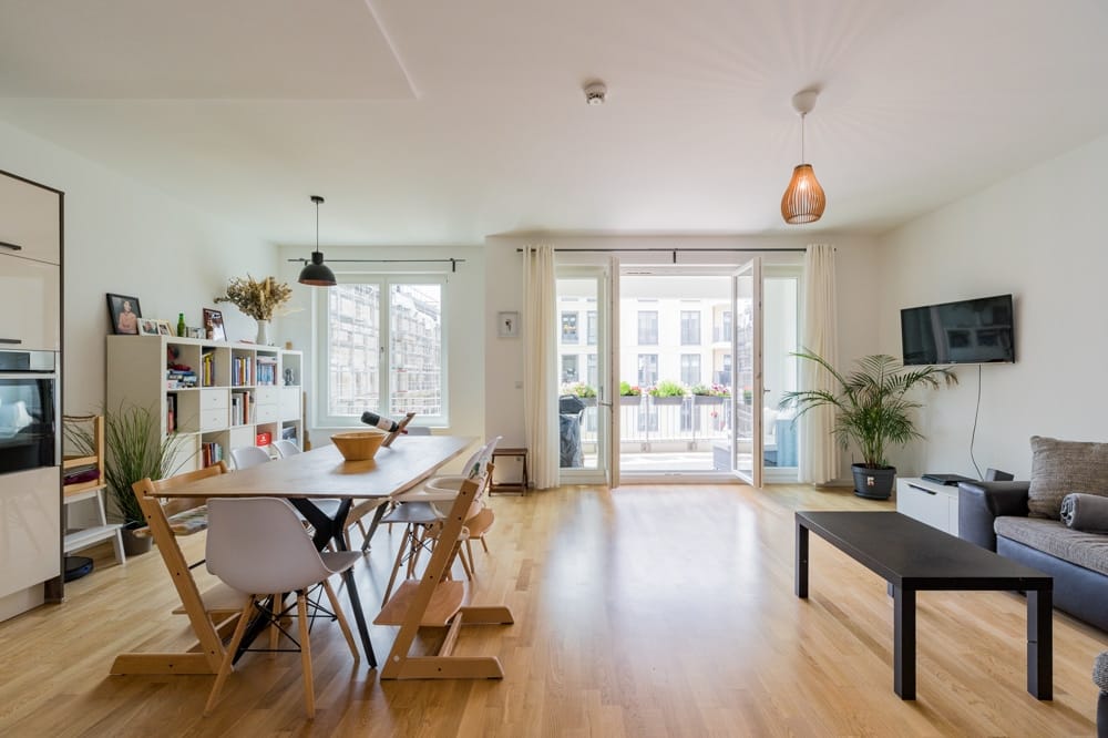 Innenaufnahme eines offenen Wohn-Essbereichs in moderner Wohnung mit Parkettboden und Balkon