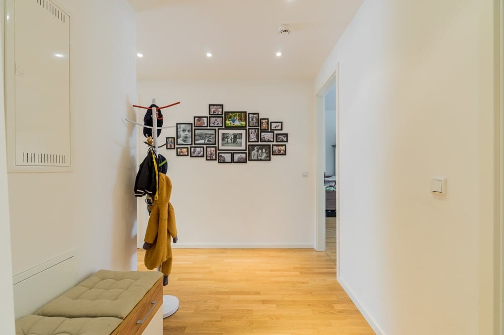 Eingangsbereich einer modernen Wohnung mit hellem Parkettboden Garderobenständer und Fotowand in Fluchtperspektive