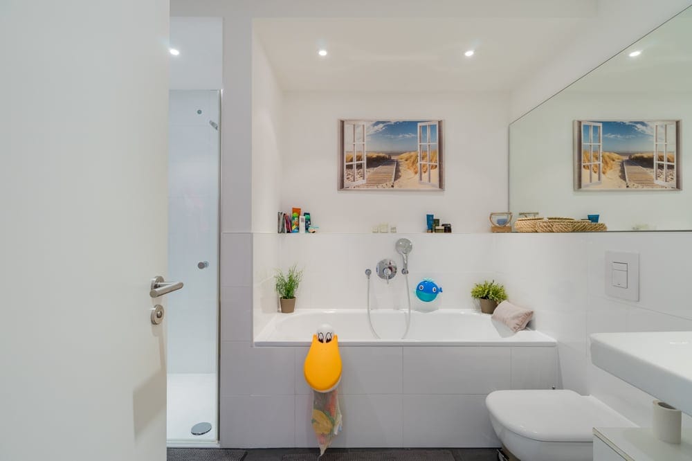 Innenansicht modernes Badezimmer mit Badewanne, Dusche, großem Spiegel und maritimem Wandbild