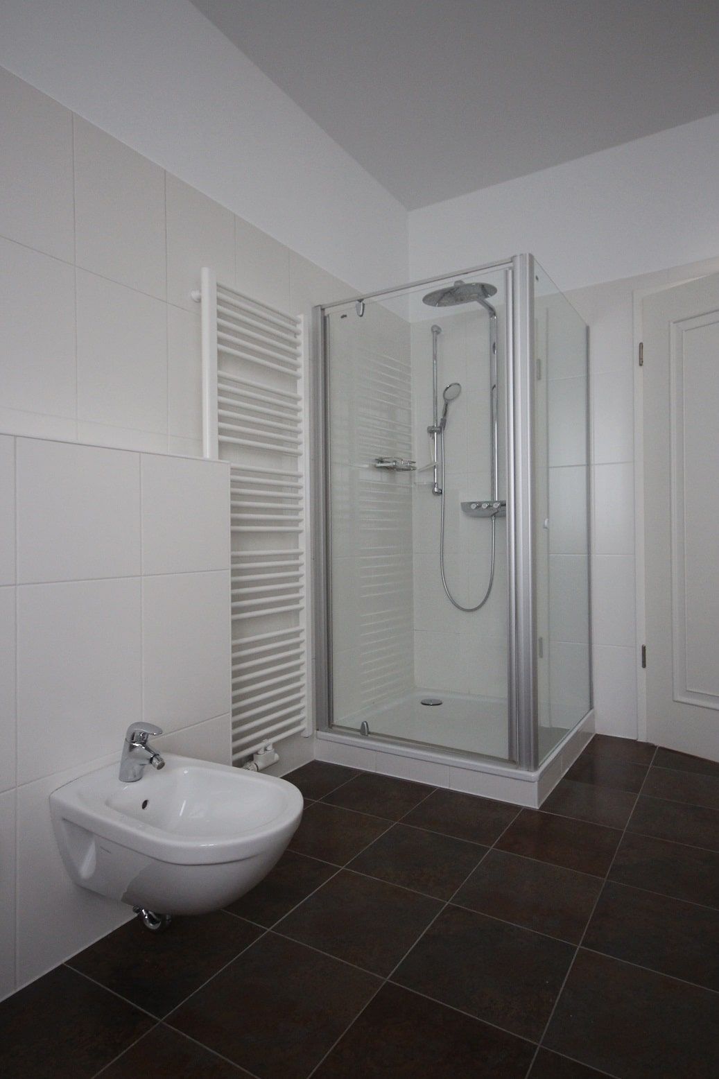 Bagno moderno bianco con cabina doccia angolare in vetro e bidet sospeso, in una chiara veduta degli interni