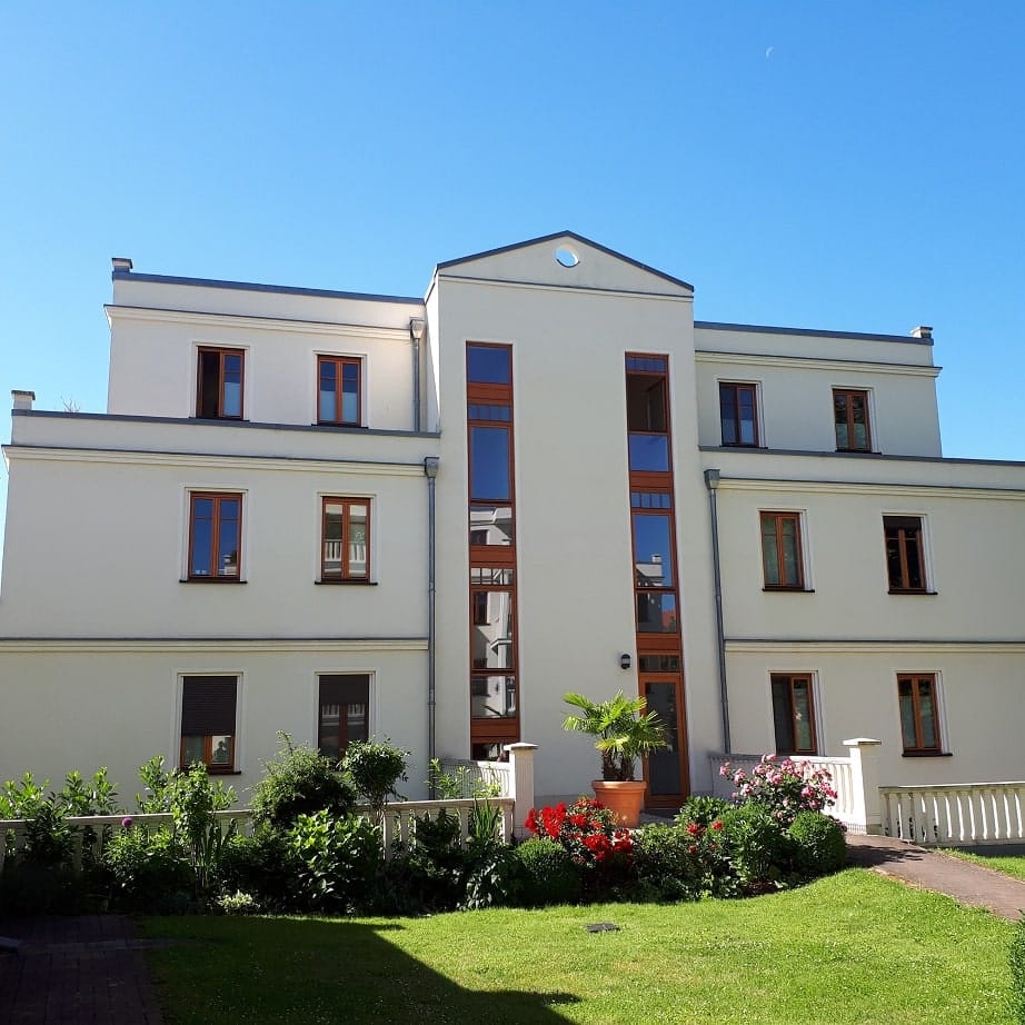 Condominio indipendente, vista frontale, facciata bianca, infissi marroni, piccolo giardino con piante in vaso