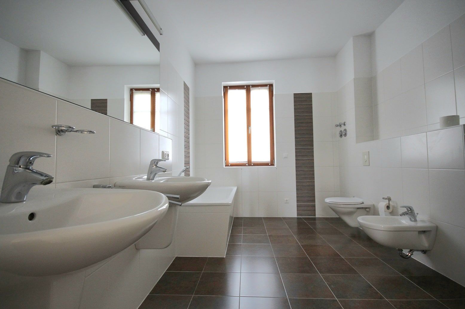 Vista interna del bagno di un appartamento piastrellato, con doppio lavabo, vasca da bagno, WC e bidet