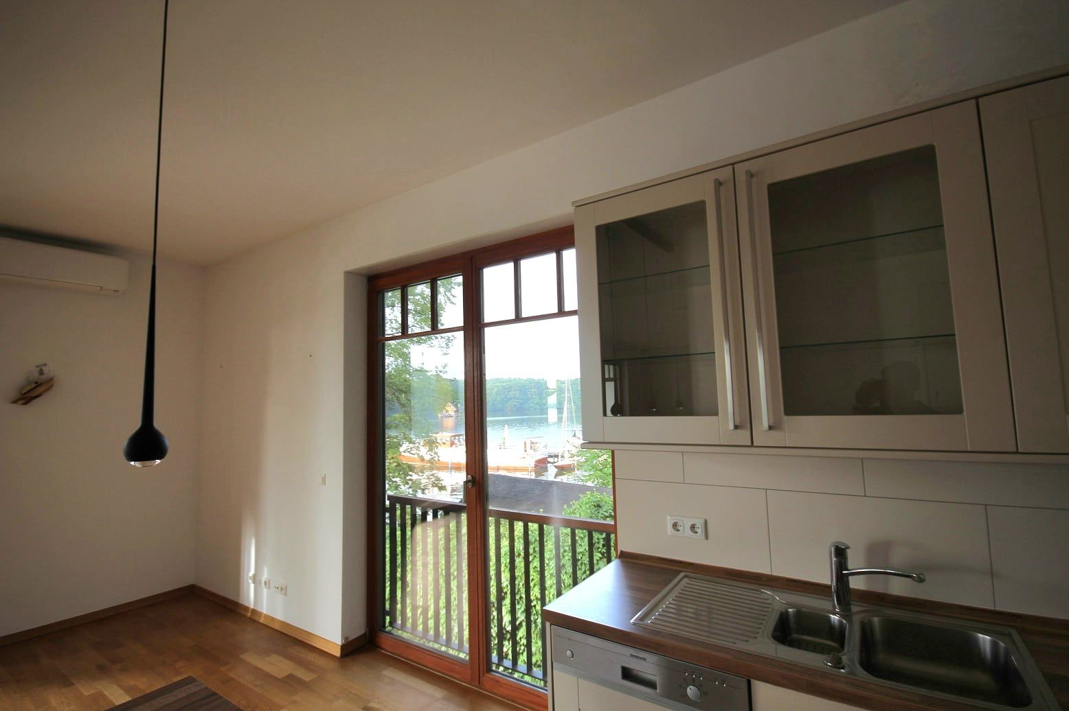 Cucina a incasso luminosa con parquet in legno e accesso al balcone con vista sul lago e sul verde
