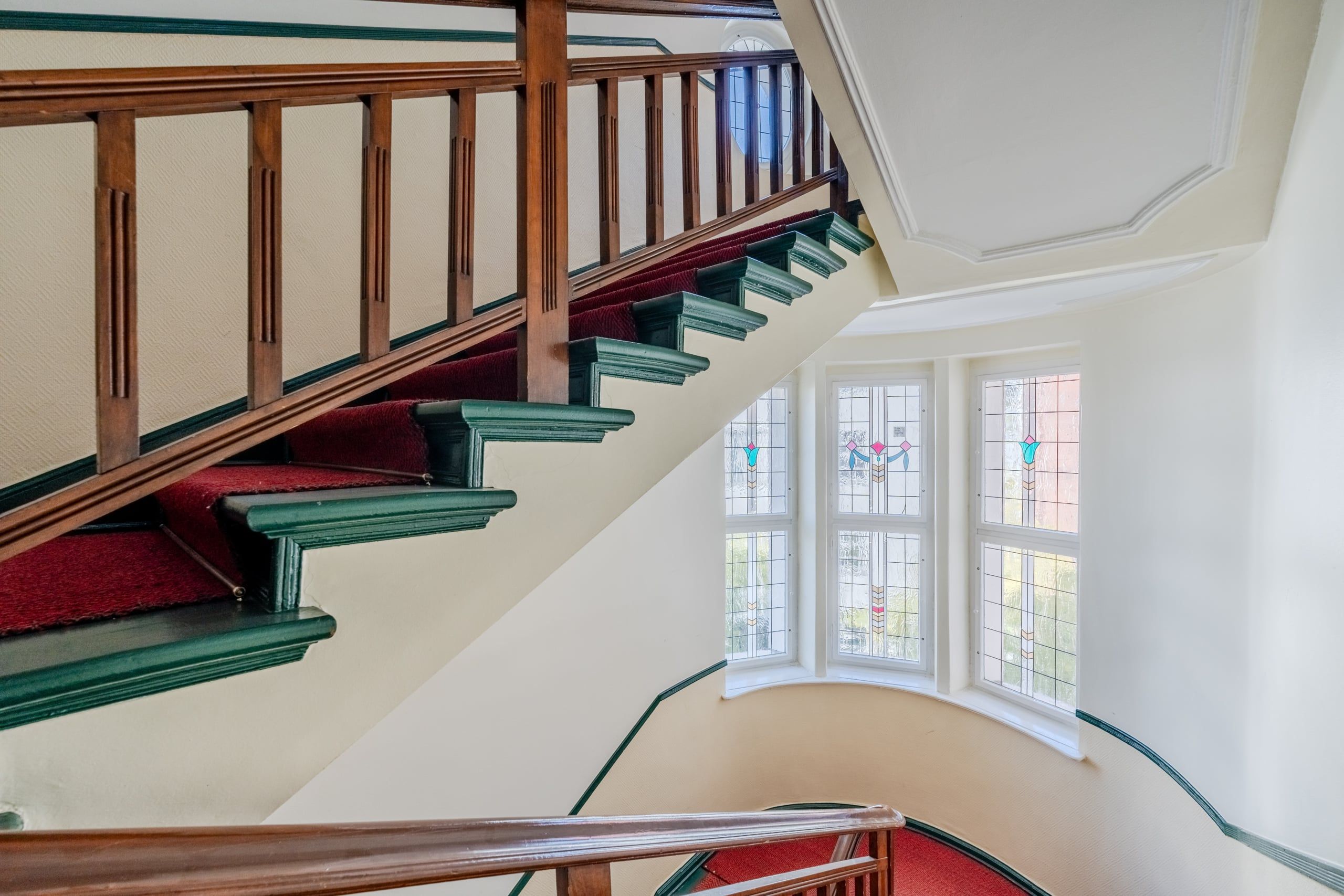 Cantiere di un edificio storico con gradini contornati di verde, moquette rossa e vetrate colorate