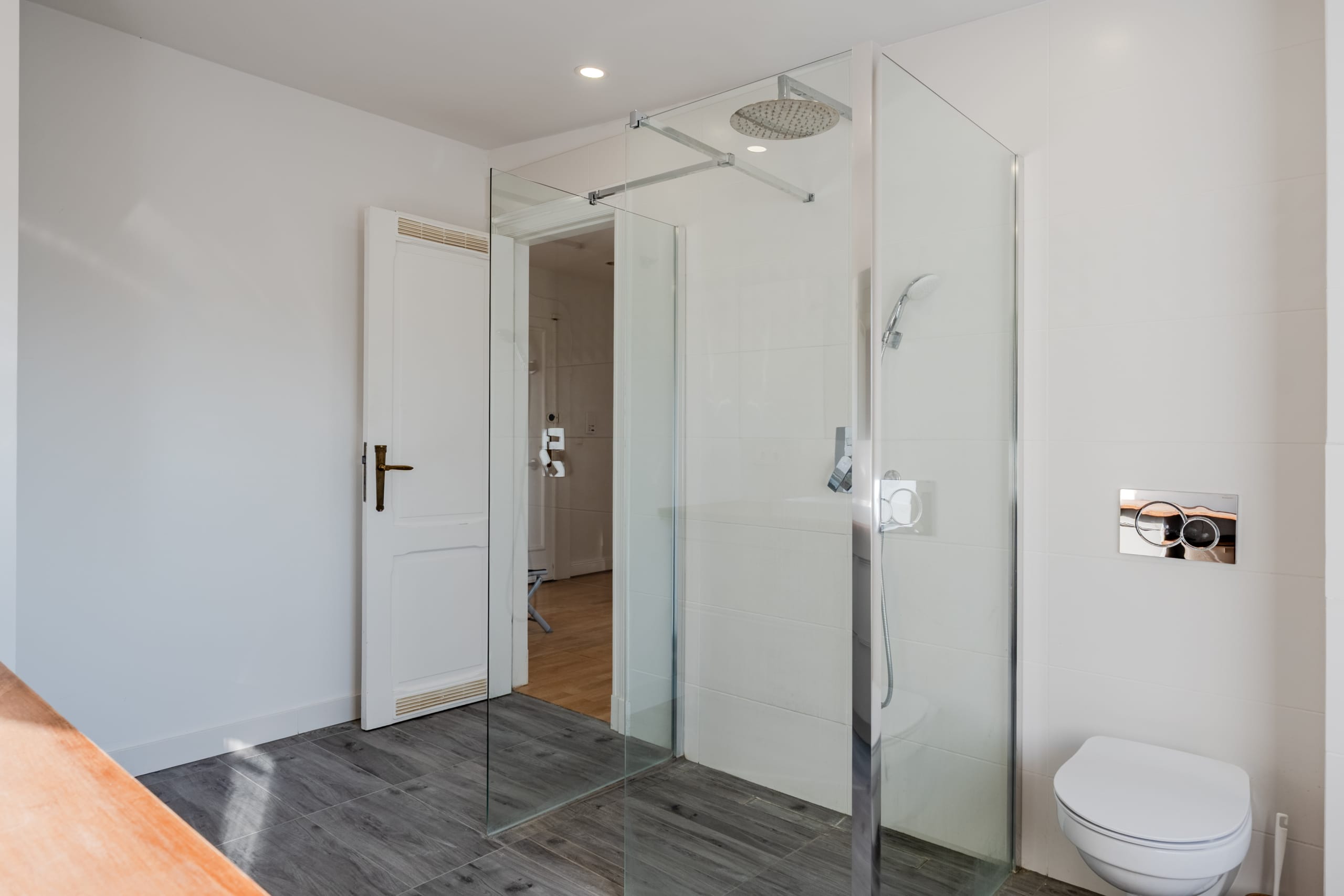 Bagno moderno con cabina doccia in vetro senza telaio e WC a parete, visto dalla porta