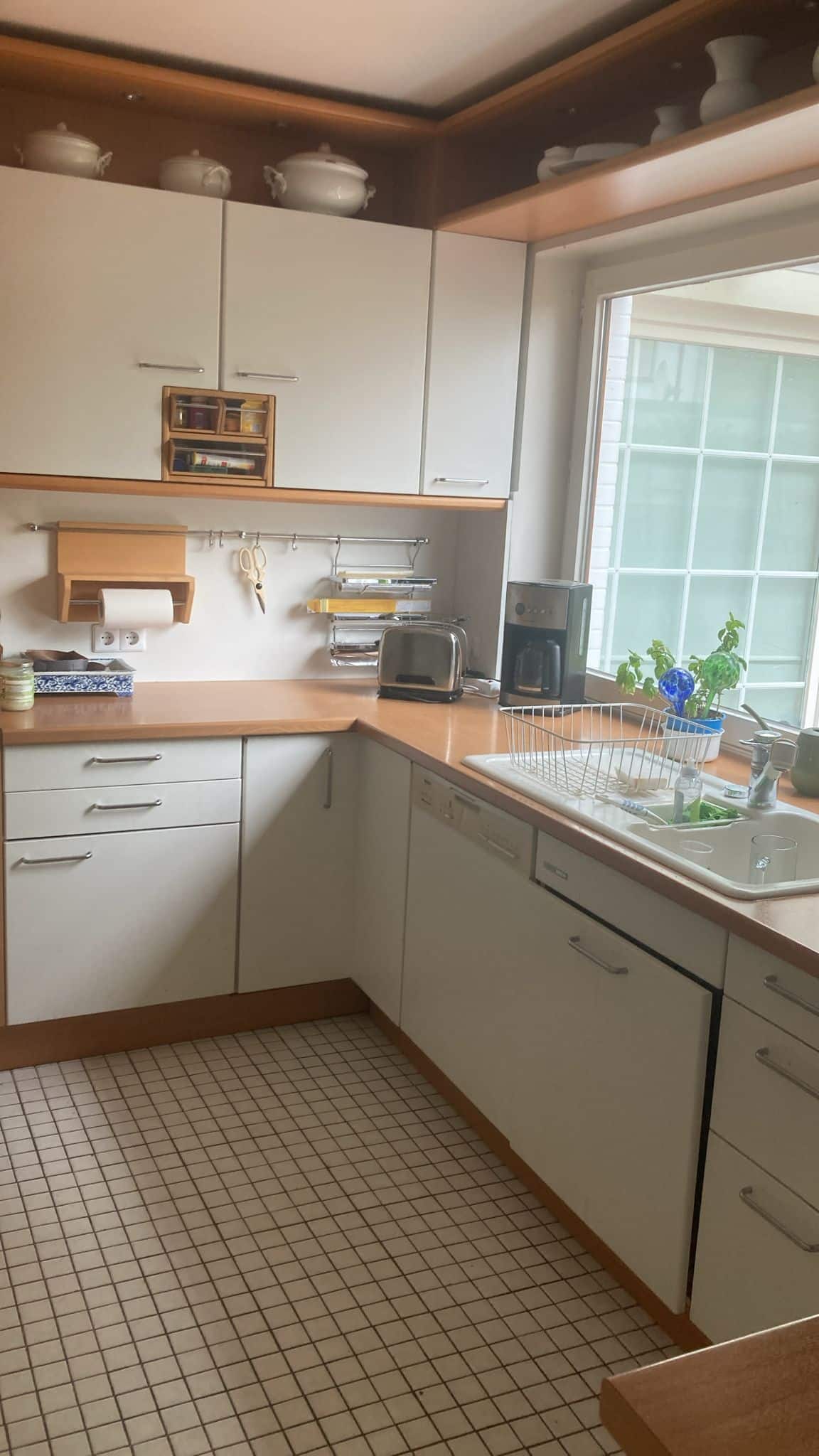 Moderne Einbauküche mit U-förmiger Anordnung weißen Fronten Holzarbeitsplatte Fliesenboden und Fensterfront