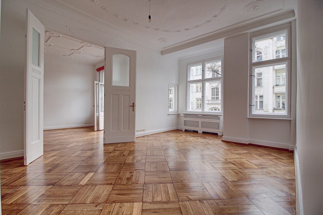 Vacant period apartment with herringbone parquet flooring, decorative ceiling, open double doors and tall windows