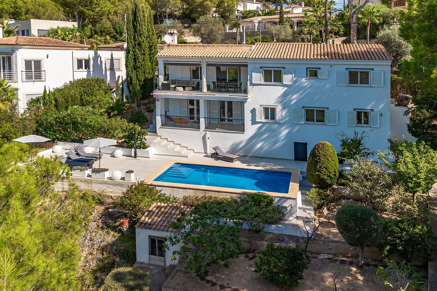 Eengezinswoning op een helling, gezien vanuit vogelperspectief, met zwembad, loungeruimte, overdekt balkon en mediterrane tuin