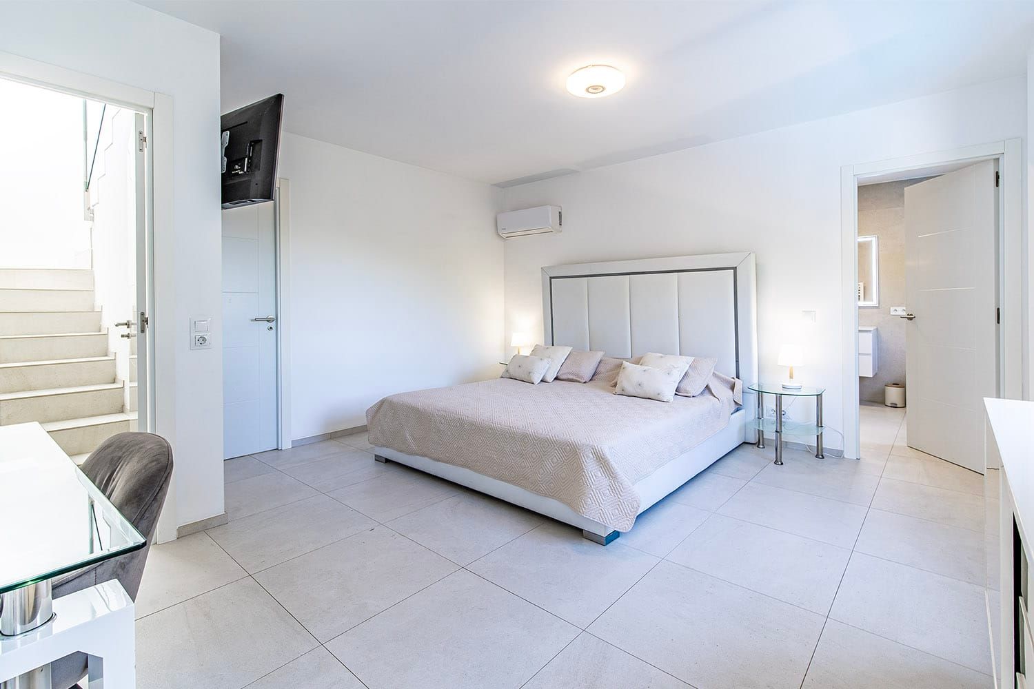 Het interieur van een moderne slaapkamer met een tweepersoonsbed, airconditioning en uitzicht op de trap en de badkamer