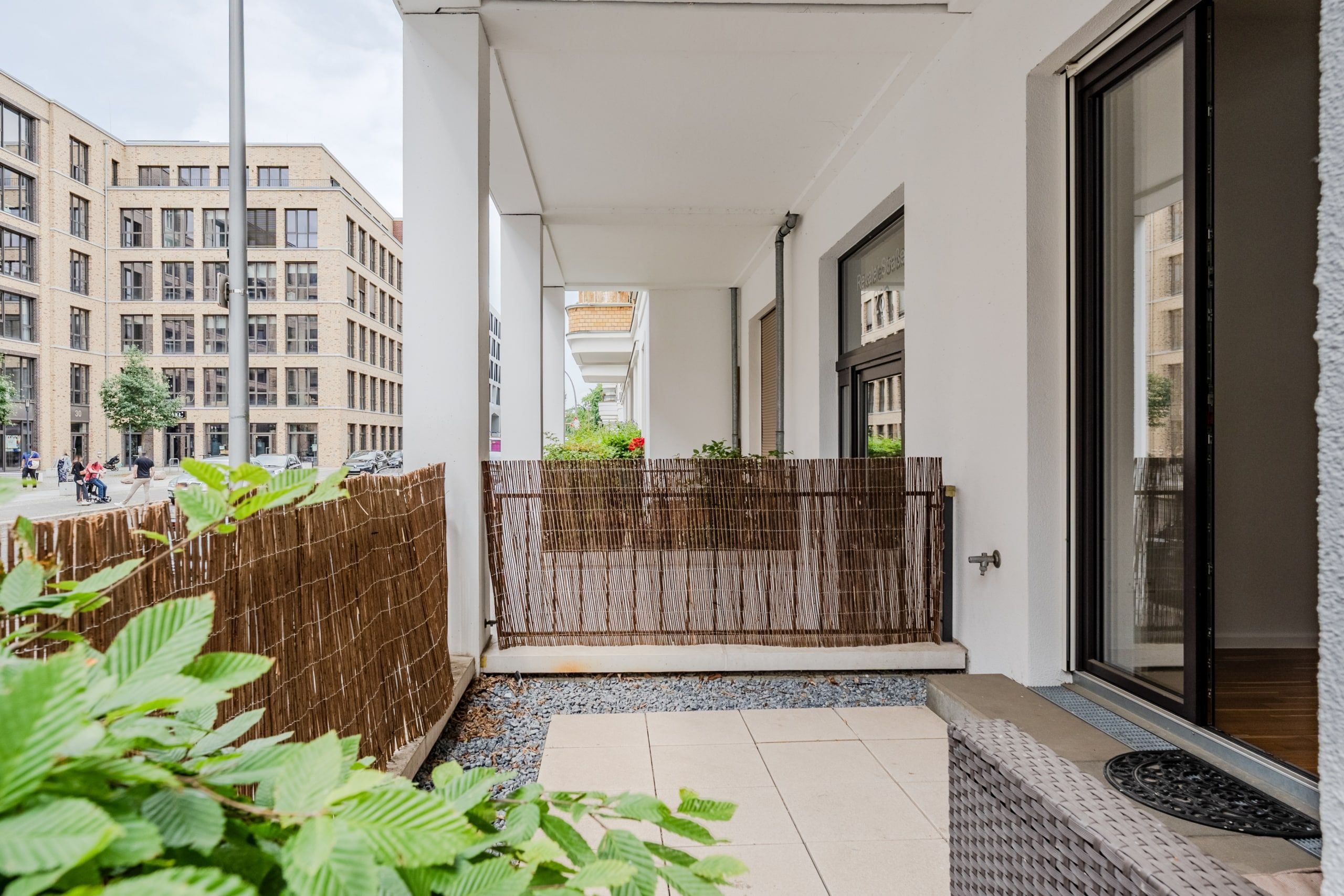 Terrassenansicht Erdgeschosswohnung mit Sichtschutz und Blick auf moderne Klinkerfassade