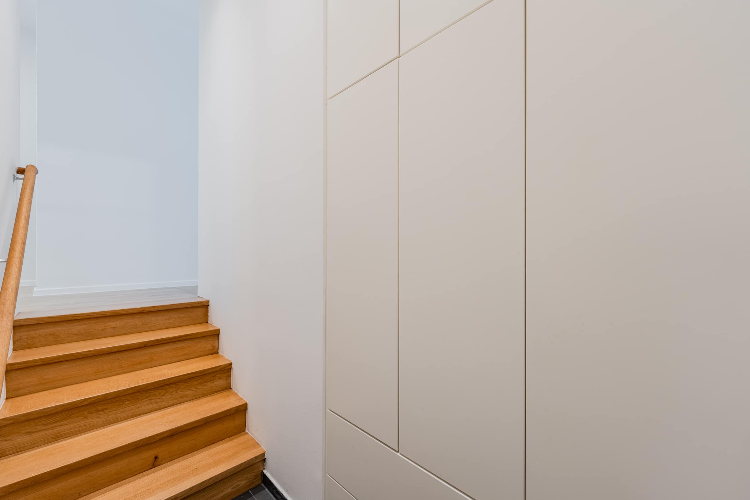 Innenansicht Flur eines Einfamilienhauses mit Eichenholztreppe und weißem Einbauschrank