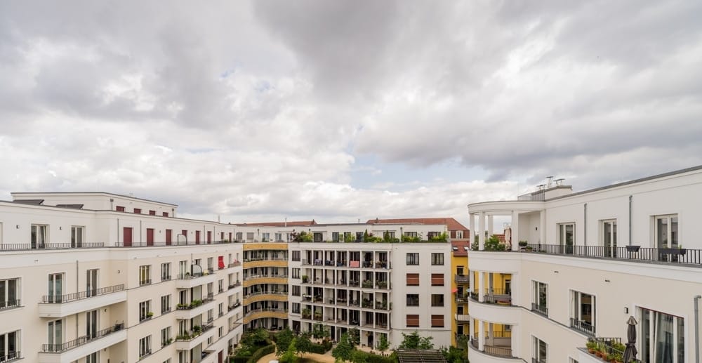 Mehrgeschossiger Wohnkomplex Innenhofperspektive mit weißen Fassaden Balkonen und begrünter Dachterrasse