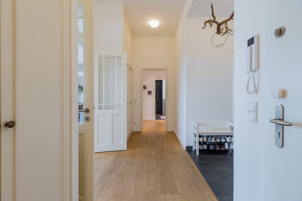 Innenansicht helle Wohnungseingang mit Holzboden Garderobenbank Schuhregal und Gegensprechanlage