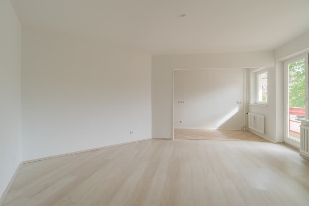 Innenansicht helle 2-Zimmer-Wohnung mit Parkettboden offener Durchgang zum Essbereich und Balkonzugang