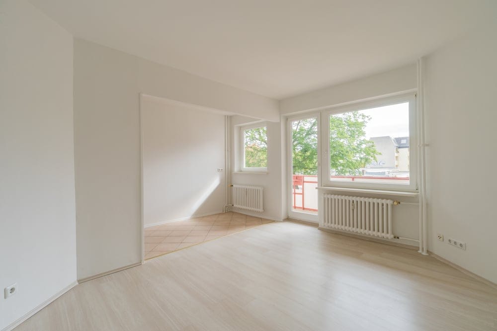 leerer heller Wohnraum in 2-Zimmer-Wohnung mit Balkonzugang großen Fenstern Laminatboden gefliester Essbereich
