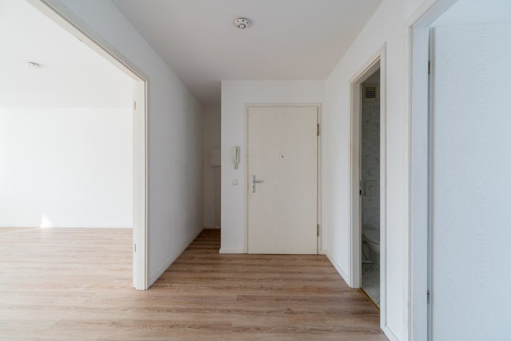 Innenansicht Wohnungseingang mit Parkettboden weiße Wände offene Zimmertüren links zum Wohnbereich rechts zum Bad