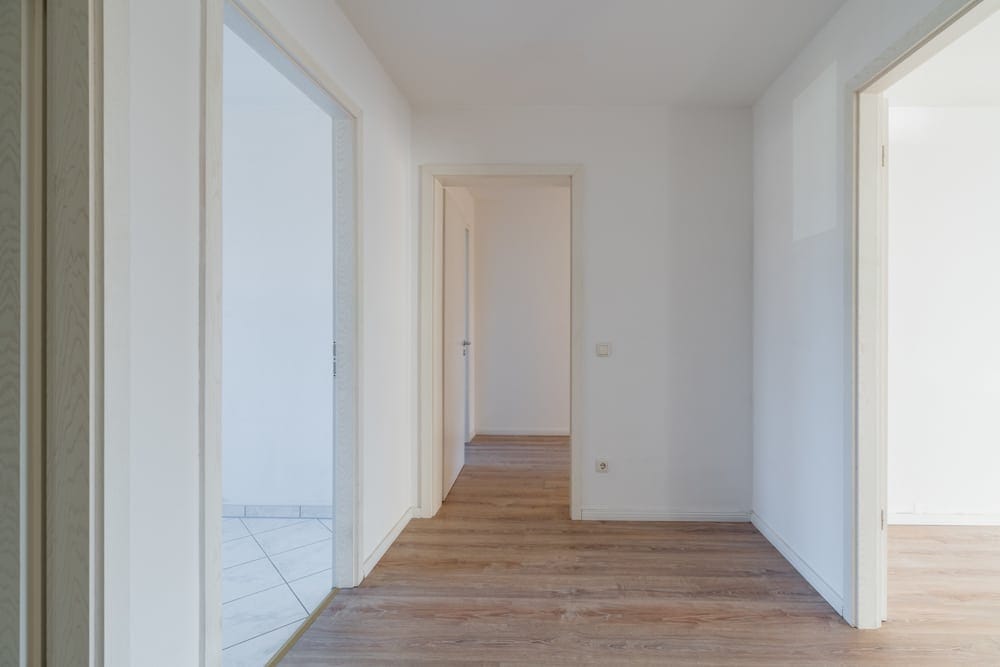 Innenansicht Flur einer leeren Wohnung mit hellem Holzfußboden und drei offenen Türen