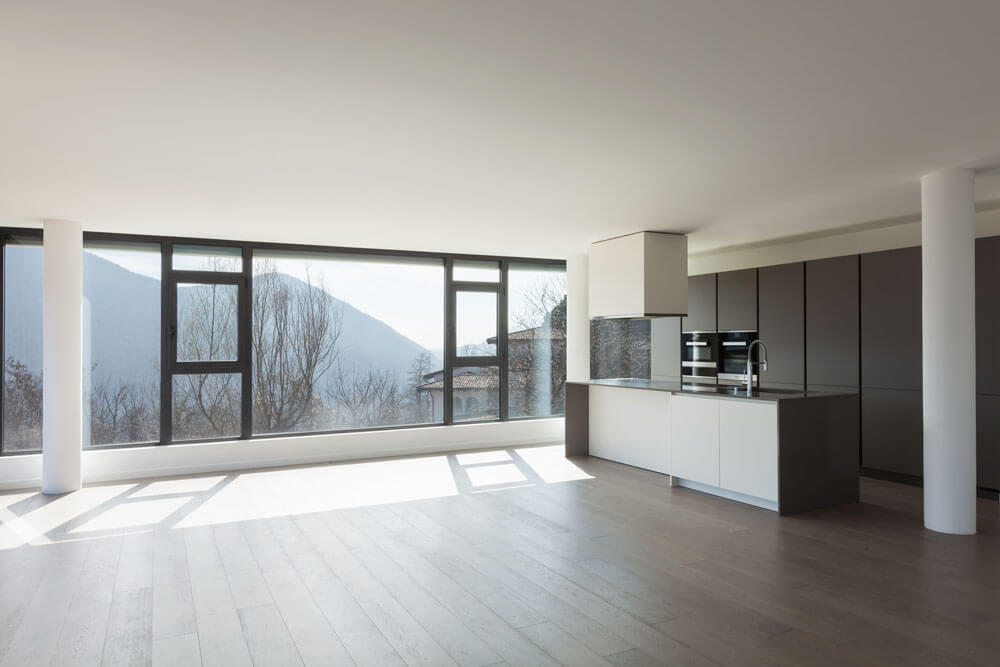 Innenansicht Neubauwohnung offene Wohnküche mit Insel und raumhoher Fensterfront mit Bergblick