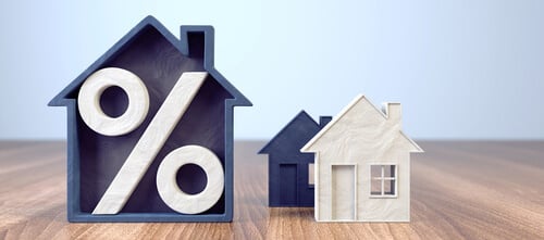 Vue frontale de modèles de maisons stylisées avec signe de pourcentage incorporé et maison miniature sur table en bois