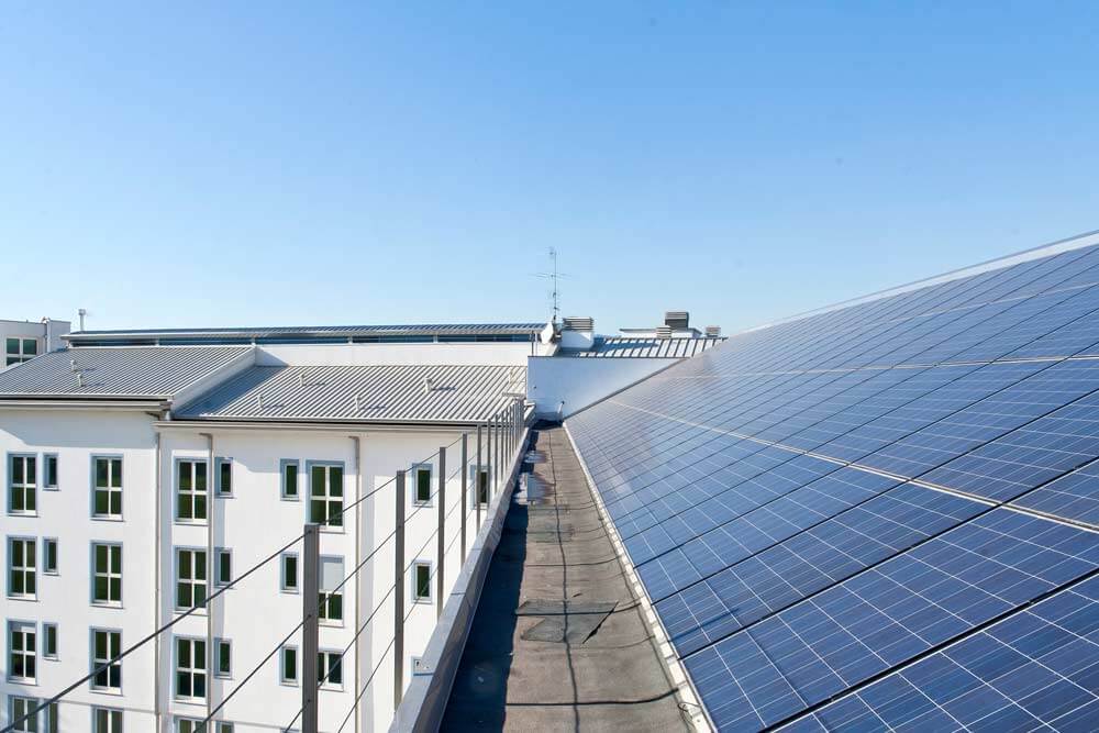 Dachperspektive auf modernes Mehrfamilienhaus mit weißen Fassaden und großflächigen Solarpaneelen