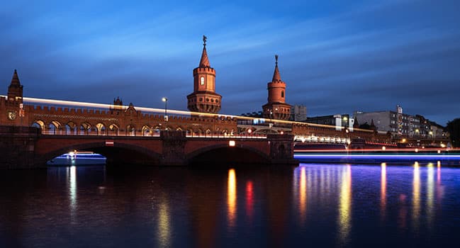 Vue de la Spree sur le pont Oberbaumbrücke Berlin au crépuscule avec une arche en briques, deux tours et un reflet dans le fleuve