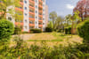 Frontansicht eines mehrgeschossigen Wohnhauses mit orangefarbenen Balkonen und Vorgarten